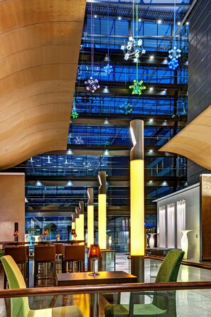 A modern interior with a high ceiling, exposed beams, and a seating area with tables and chairs. - Hilton Frankfurt Airport (Frankfurt)