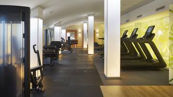 A gym with treadmills, weight machines, and a mirrored wall.