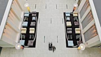 A top-down view of a hotel lobby with two seating areas, each with a sofa and a table, and a central walkway.