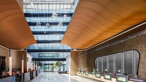 A spacious hotel lobby with a modern design, featuring a glass ceiling, a reception desk, and a seating area. - Hilton Frankfurt Airport (Frankfurt)