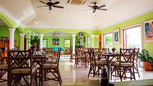 A spacious dining area with high ceilings, ceiling fans, and large windows. - The Villas at Sunset Lane (St. John's)