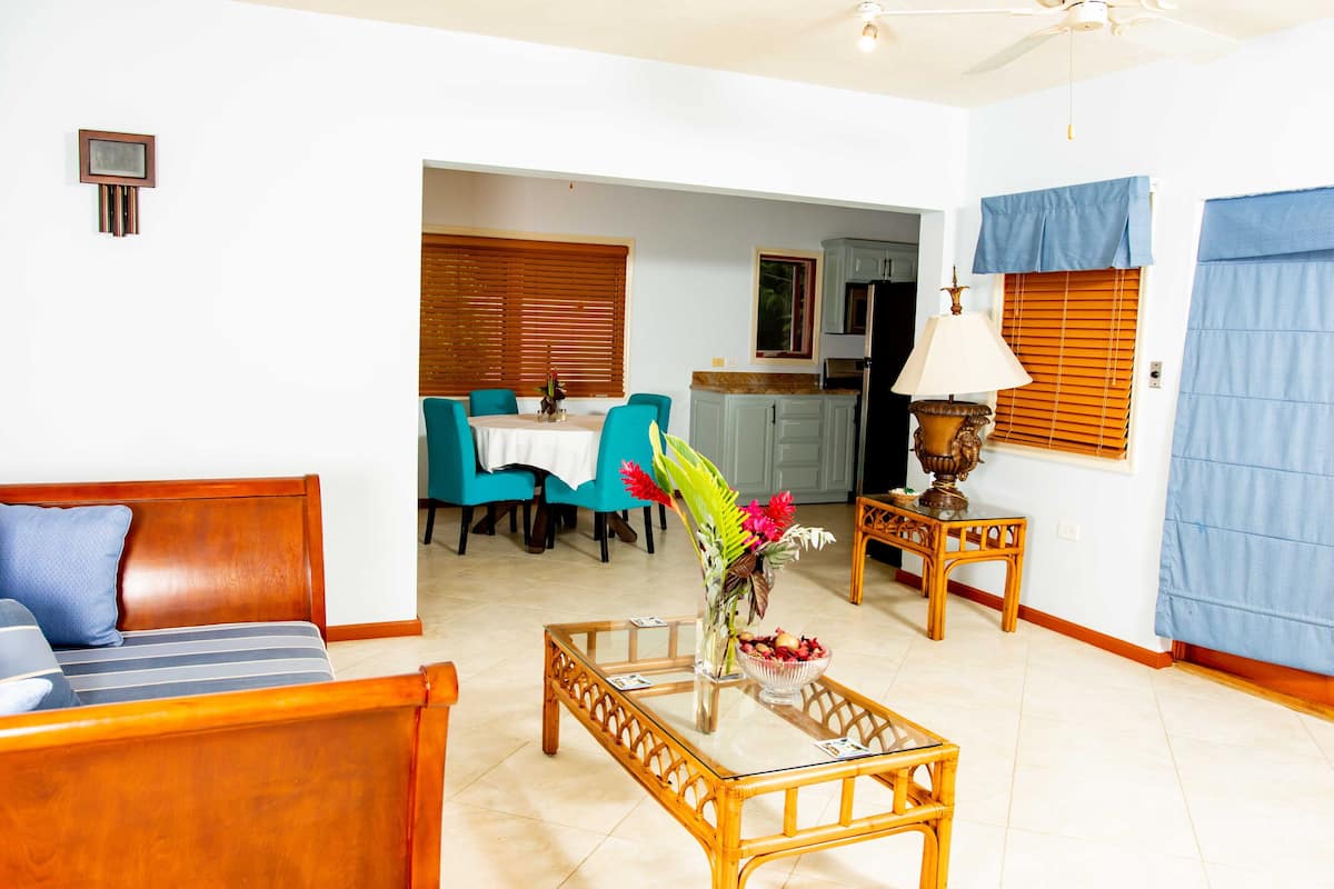 A living room with a sofa, a glass coffee table, and a dining area with a table and chairs.