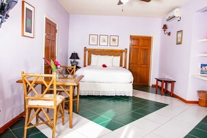 Un dormitorio con una cama, una silla de madera, una mesita y una lámpara de pared.