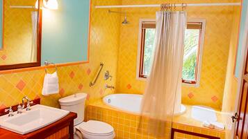 A bathroom with yellow tiles, a white sink, a toilet, a bathtub, and a shower.