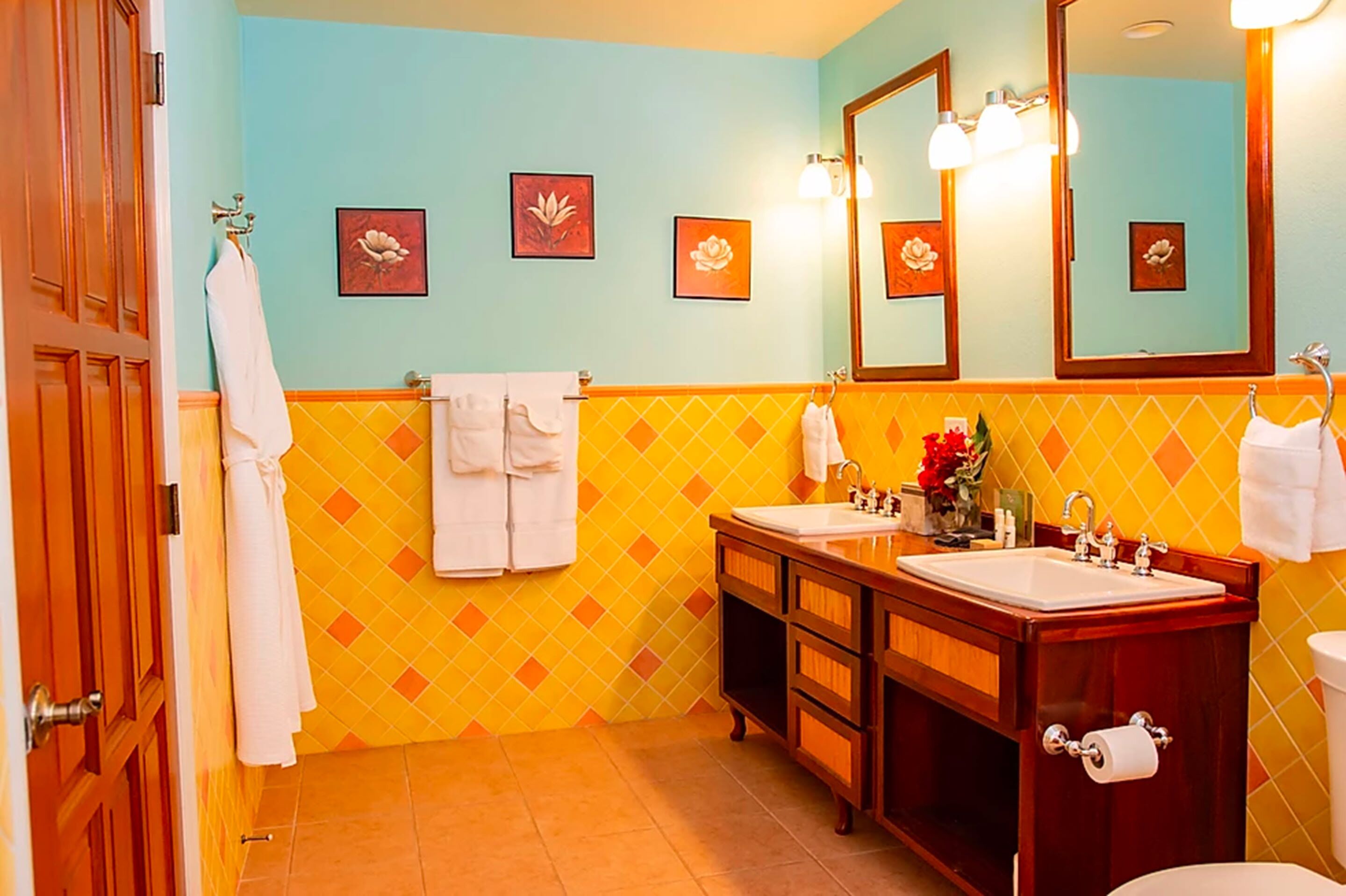 Une salle de bain avec deux lavabos, un grand miroir et un sol carrelé.