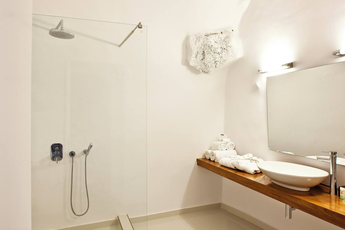Ein modernes Badezimmer mit Dusche, einem Holzkosmetikschrank, einem Waschbecken und einem Spiegel.
