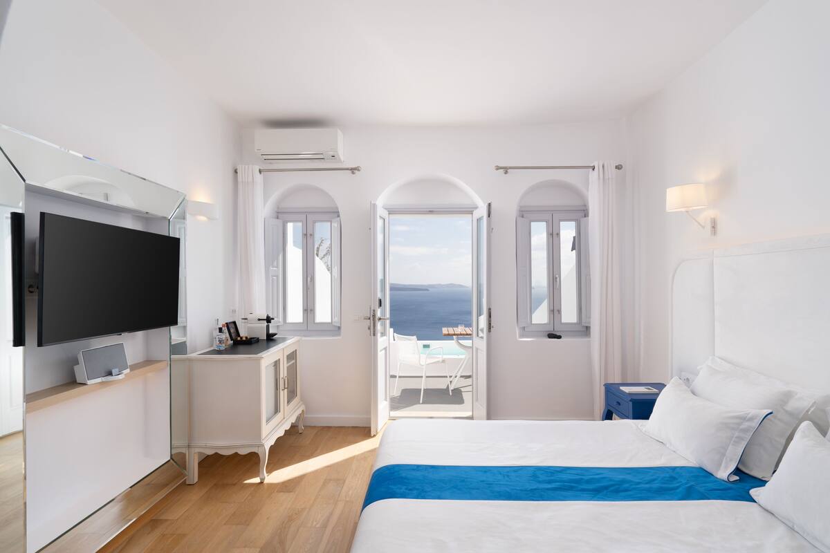 Ein modernes Hotelzimmer mit Bett, Fernseher und einem Balkon mit Blick.