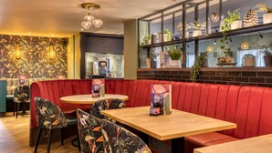 Un restaurant avec des banquettes rouges, des tables en bois et des chaises à motifs floraux.