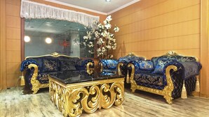 Een luxueuze kamer met gedetailleerd blauw en gouden meubilair, een glazen bijzettafeltje en een grote spiegel.