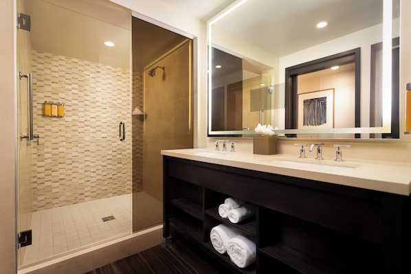 A modern bathroom with a glass-enclosed shower, a large mirror, and a vanity with a sink and towel storage.