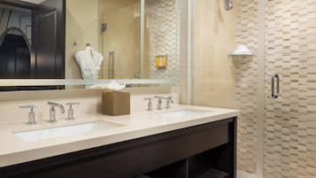 Une salle de bain moderne avec deux lavabos, un grand miroir et une douche à parois de verre.