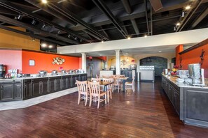 A spacious kitchen with a long counter, wooden chairs, and a dining table.