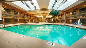 An indoor swimming pool with a glass ceiling, surrounded by lounge chairs and a central plant. - Best Western Plus Raton Hotel (Raton)