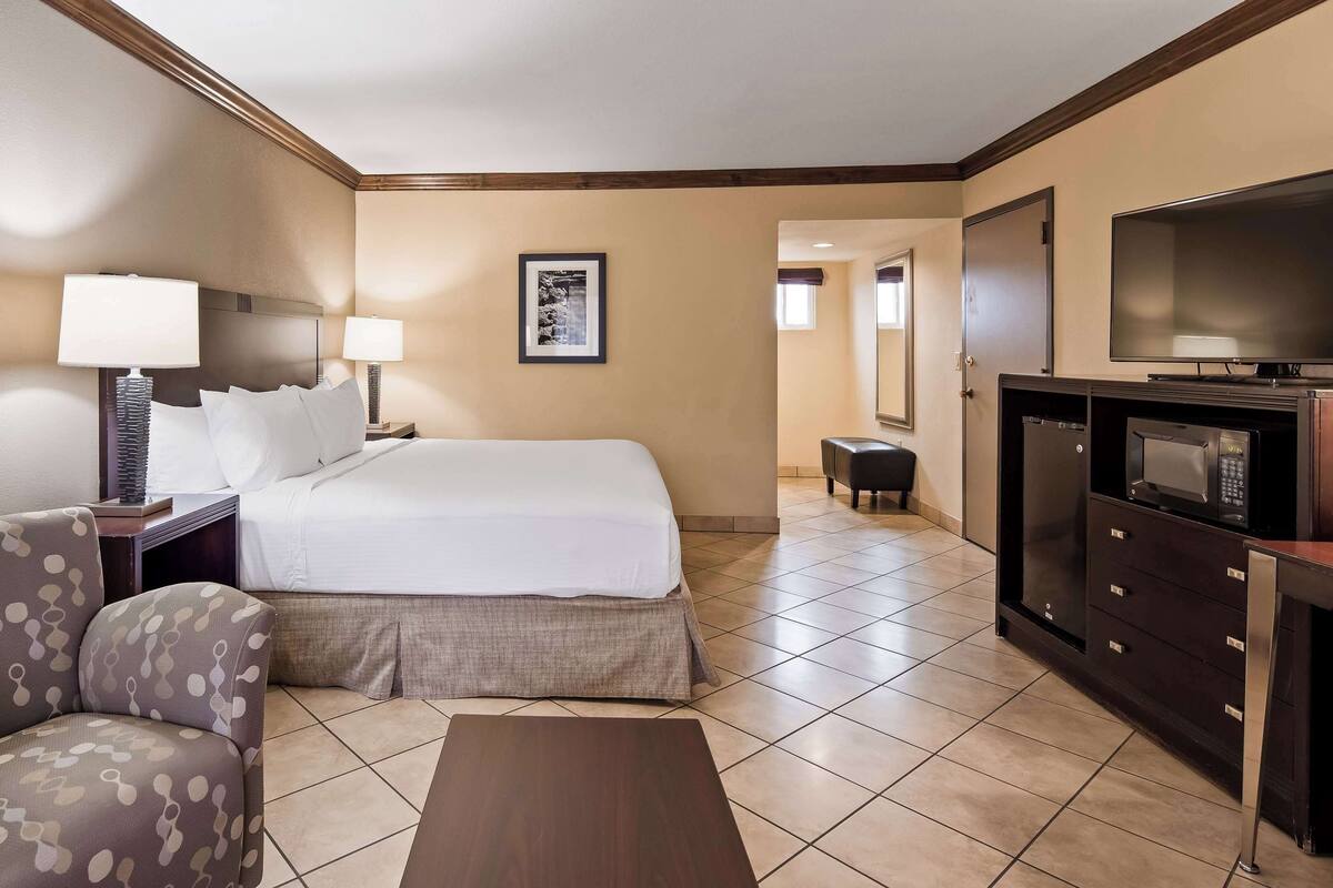 A hotel room with a bed, a TV, a desk, a chair, and a small table.