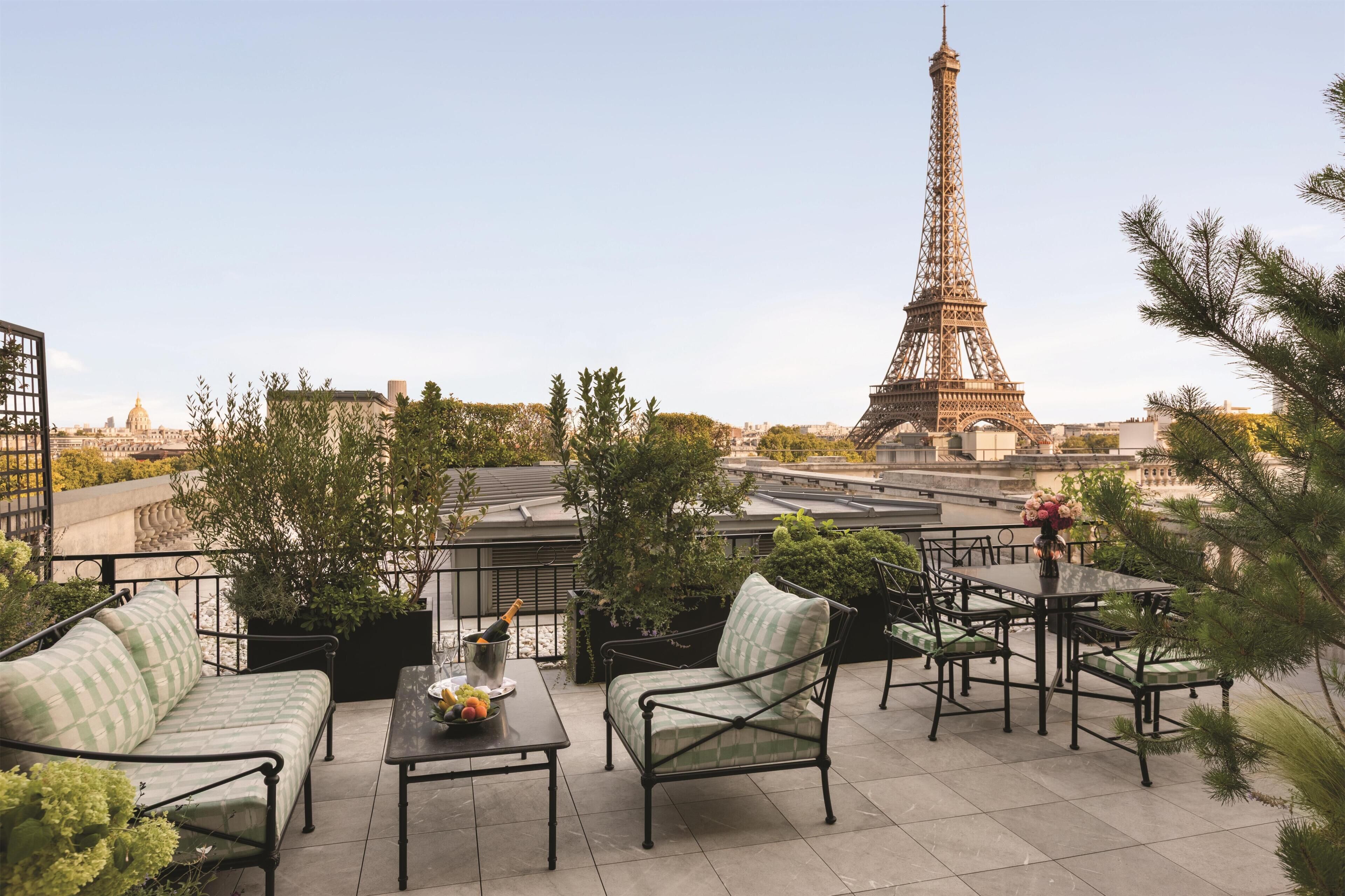 A rooftop terrace with outdoor furniture, a view of the Eiffel Tower, and potted plants.