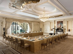 A formal meeting room with a long table, ornate ceiling, and classical decor.