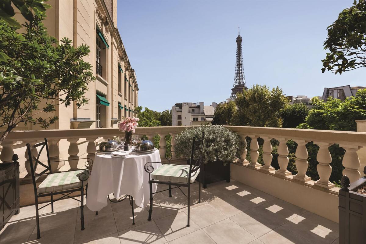 Une terrasse avec une table et des chaises, un pot de fleurs et une vue sur la Tour Eiffel.