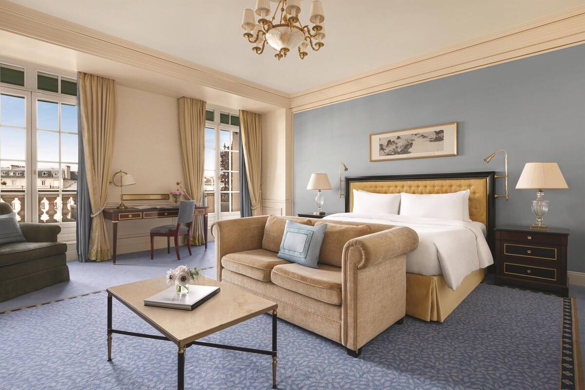 Une chambre d’hôtel avec un lit, un bureau, un canapé, une table basse et une vue sur la ville.