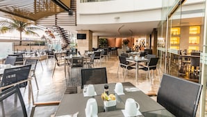 A spacious indoor dining area with multiple tables and chairs, a staircase, and a view of the outside.