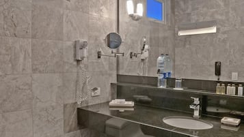 Une salle de bain moderne avec un mur en marbre, un grand miroir, des toilettes et un lavabo.