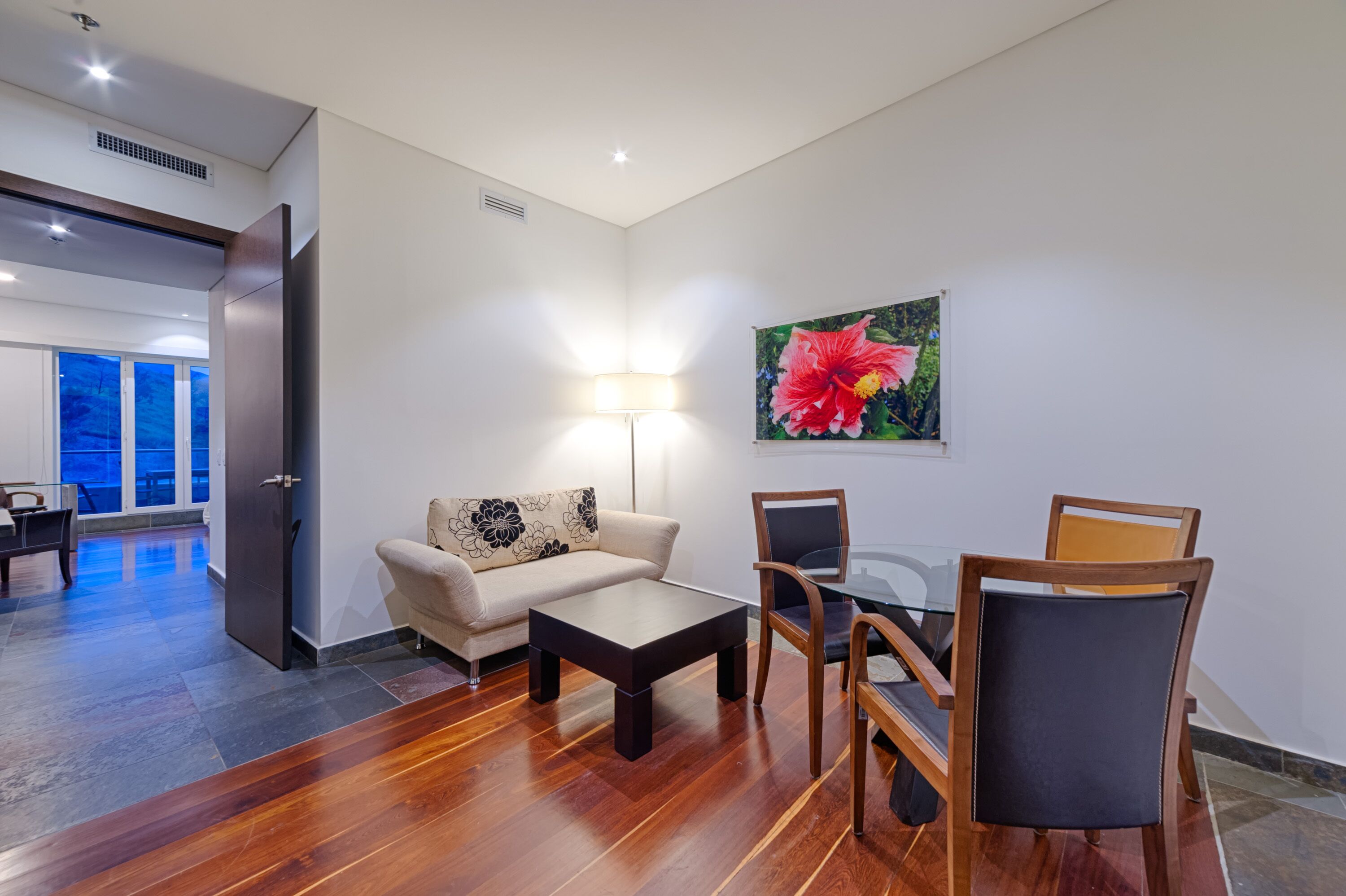 A modern living room with a sofa, coffee table, and dining set.