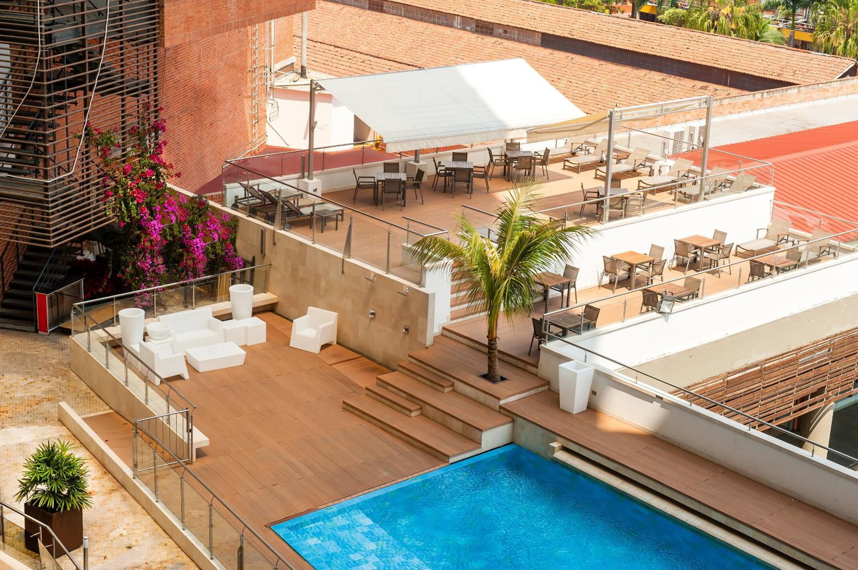 A rooftop pool area with outdoor seating and a view of the cityscape.
