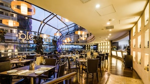 A modern restaurant with a high ceiling, large windows, and a variety of seating arrangements.