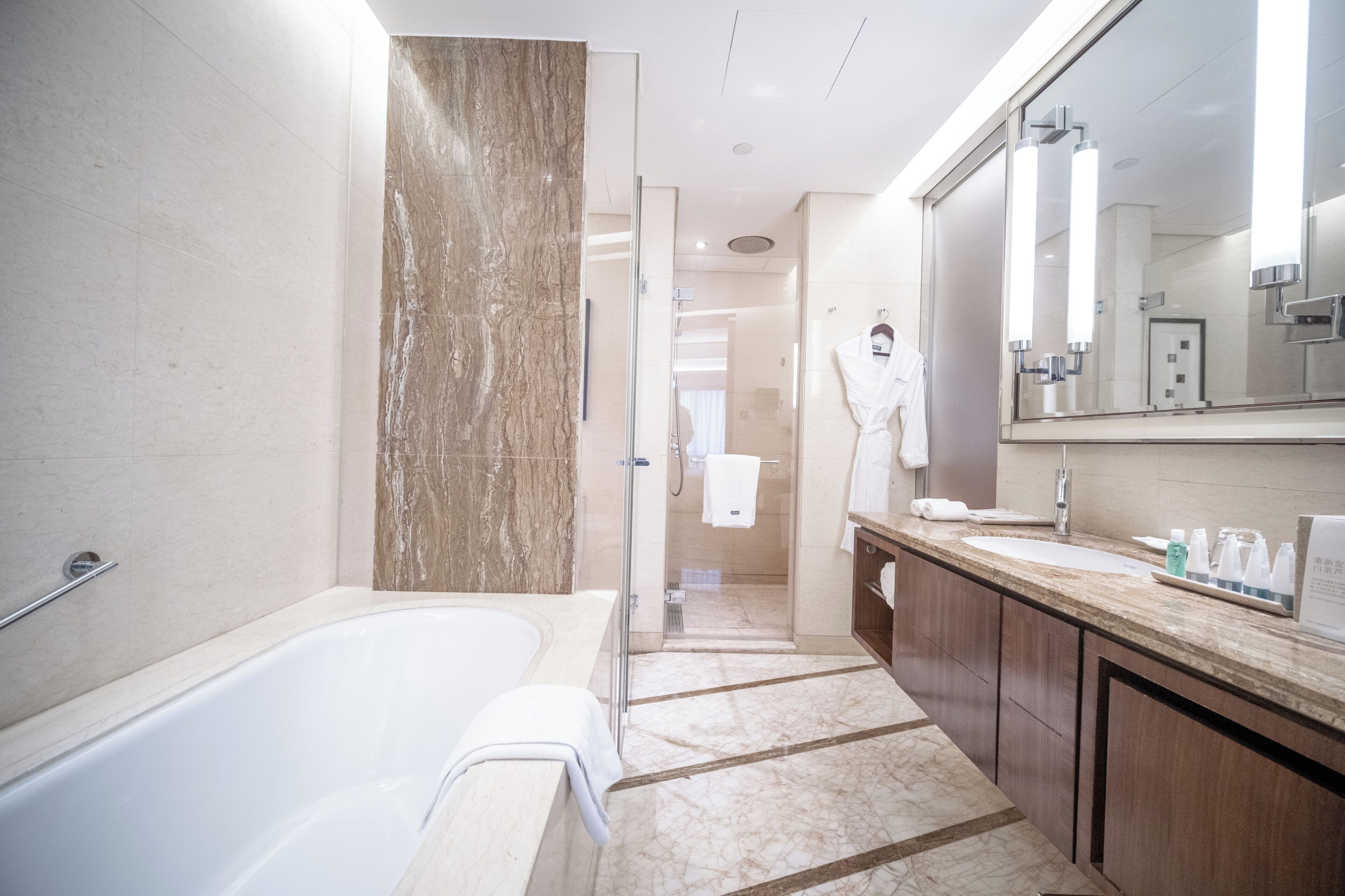 Un baño moderno con una bañera, ducha, tocador con espejo y un perchero para toallas.