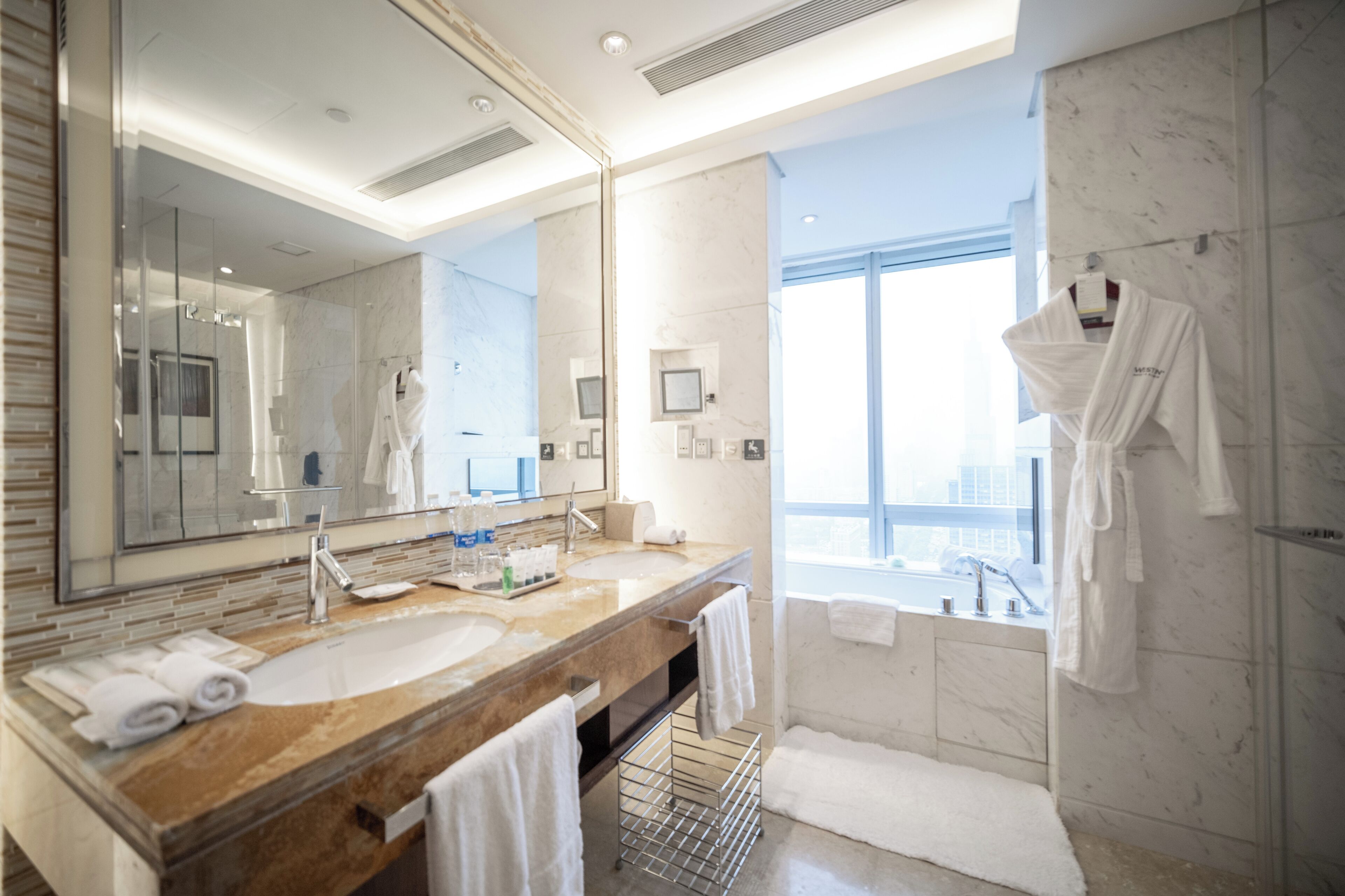 Un baño moderno con un espejo grande, lavamanos de mármol y ducha a ras de suelo.