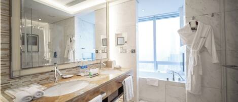 Un baño moderno con un espejo grande, lavamanos de mármol y ducha a ras de suelo.
