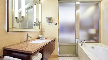 Un baño moderno con lavamanos de mármol, un espejo grande, una bañera y una puerta de ducha con vidrio esmerilado.