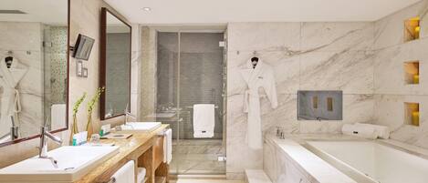 A modern bathroom with a marble sink, a large mirror, a glass-enclosed shower, and a separate bathtub.