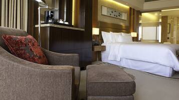A hotel room with a bed, a sofa, a coffee machine, and a nightstand.