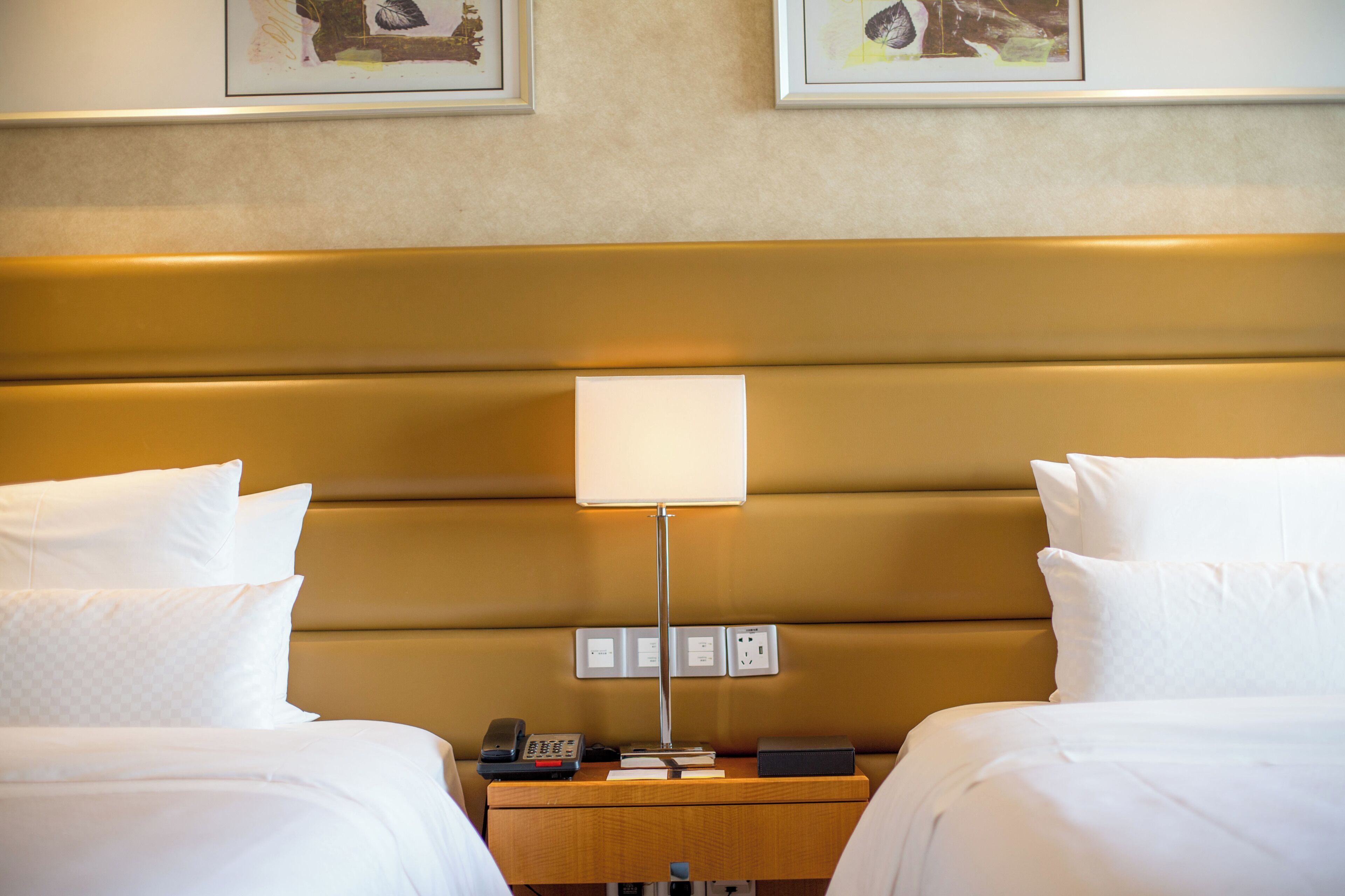 Ein Hotelzimmer mit zwei Betten, einem Nachttisch mit Lampe, Telefon und Buch.