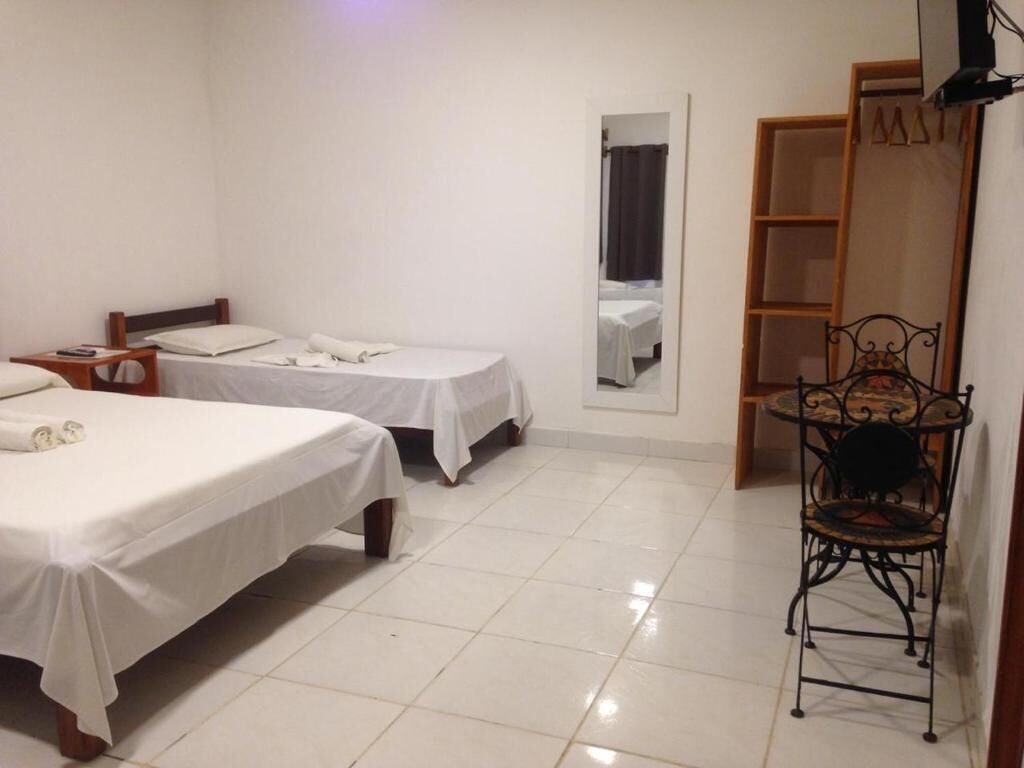 Habitación de hotel con dos camas individuales, una mesita con una silla y un armario.