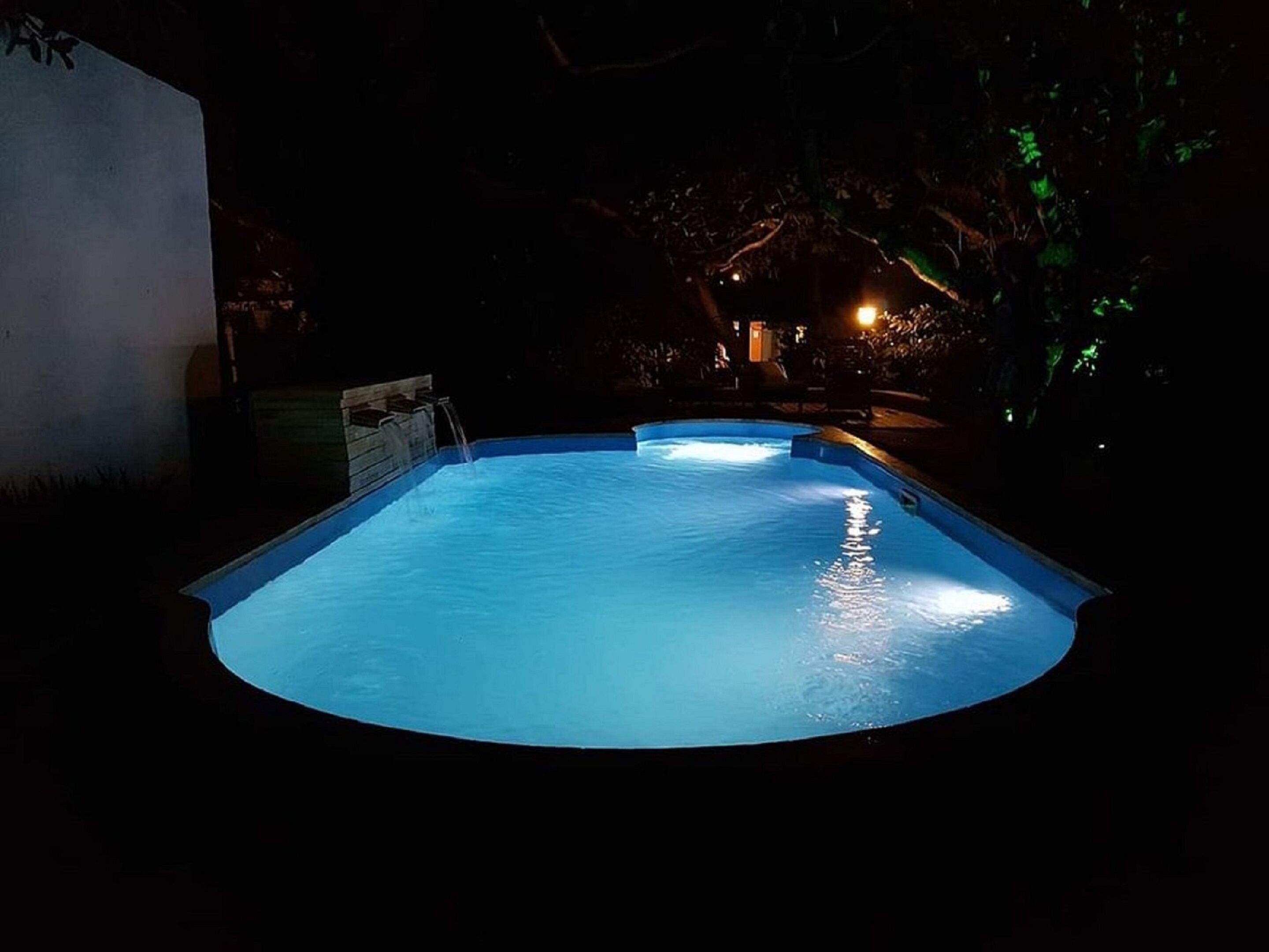 A swimming pool at night with a water feature.