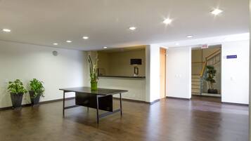 Um quarto espaçoso com piso de madeira, um balcão de recepção e plantas em vasos.