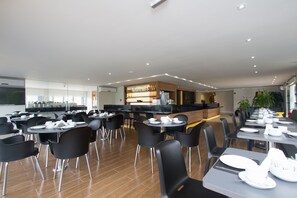 A modern dining area with tables and chairs, a bar area, and a kitchen in the background. - Le Canard Joinville (Joinville)