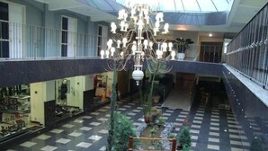 A multi-level atrium with a central garden, a chandelier, and retail stores on the upper level. - Hotel Águas Virtuosas (Lambari)