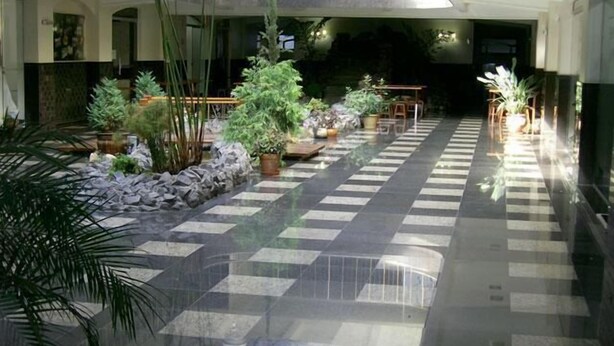 A spacious indoor area with a checkered floor, potted plants, and a staircase leading to an upper level. - Hotel Águas Virtuosas (Lambari)