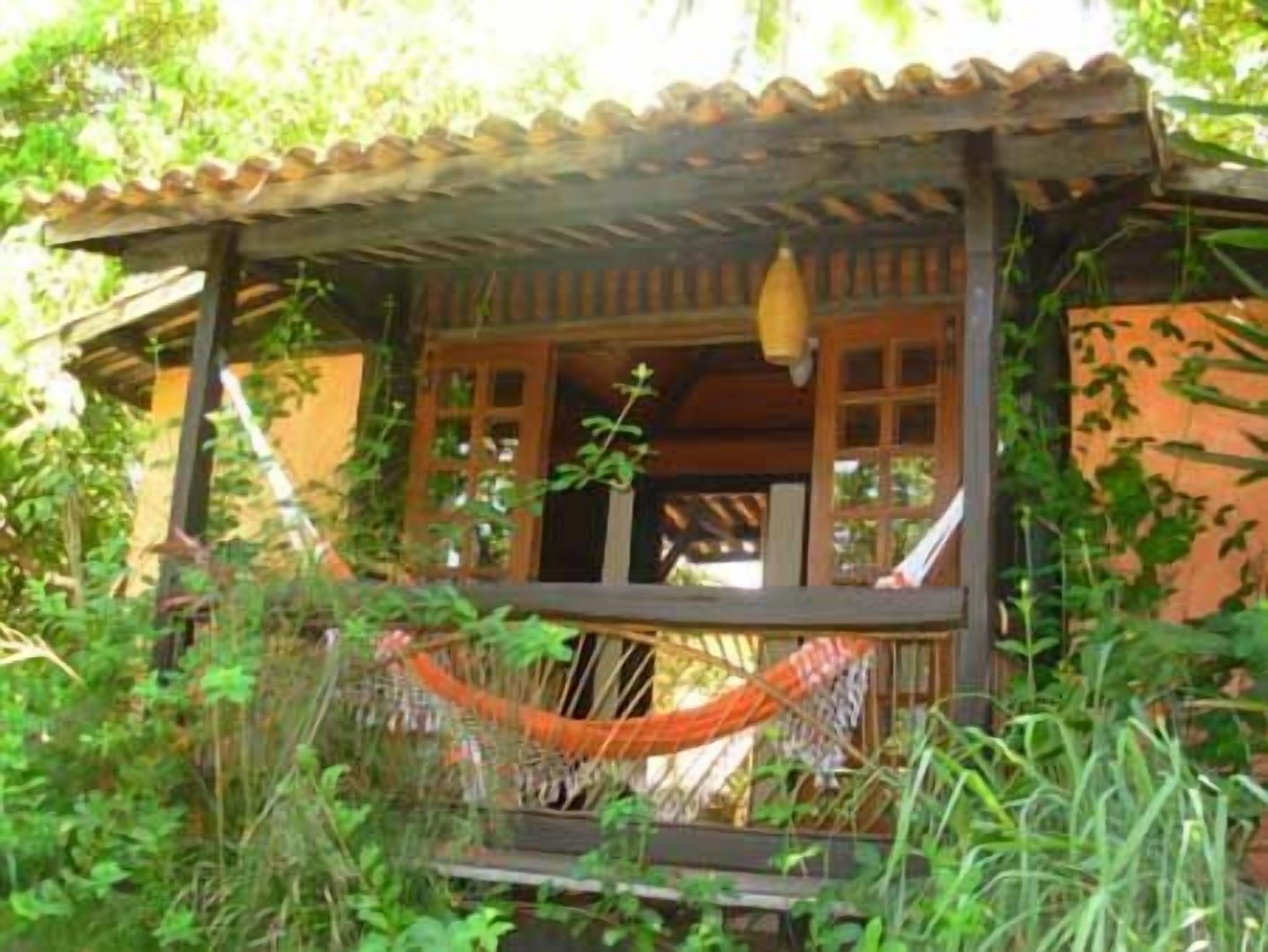 A wooden cabin with a porch, surrounded by greenery.