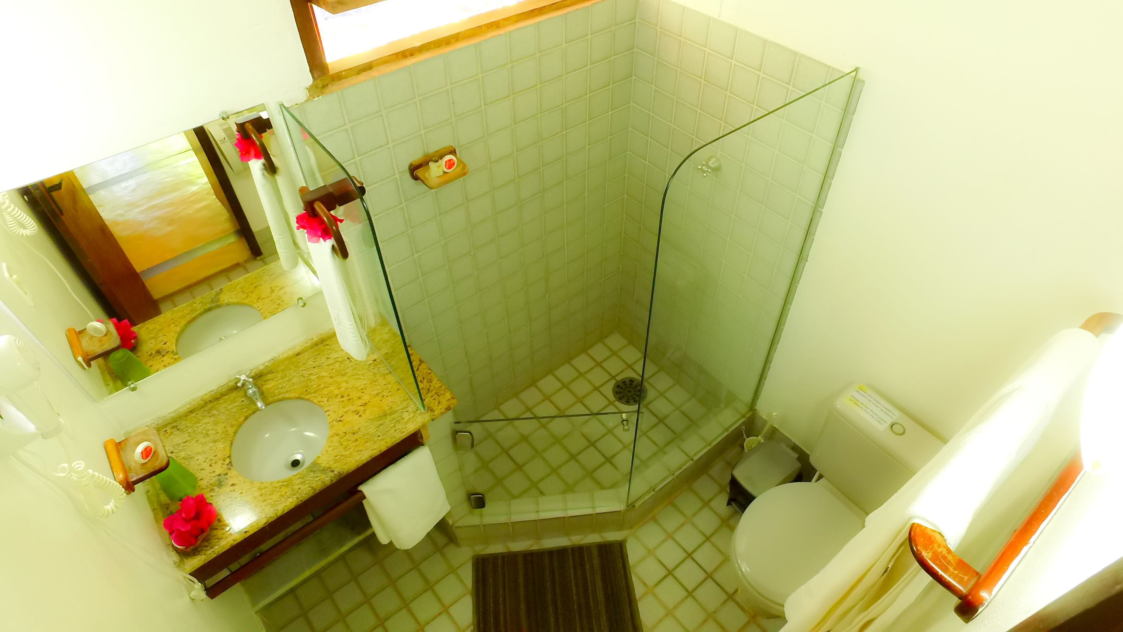 A bathroom with a shower, toilet, sink, and mirror.