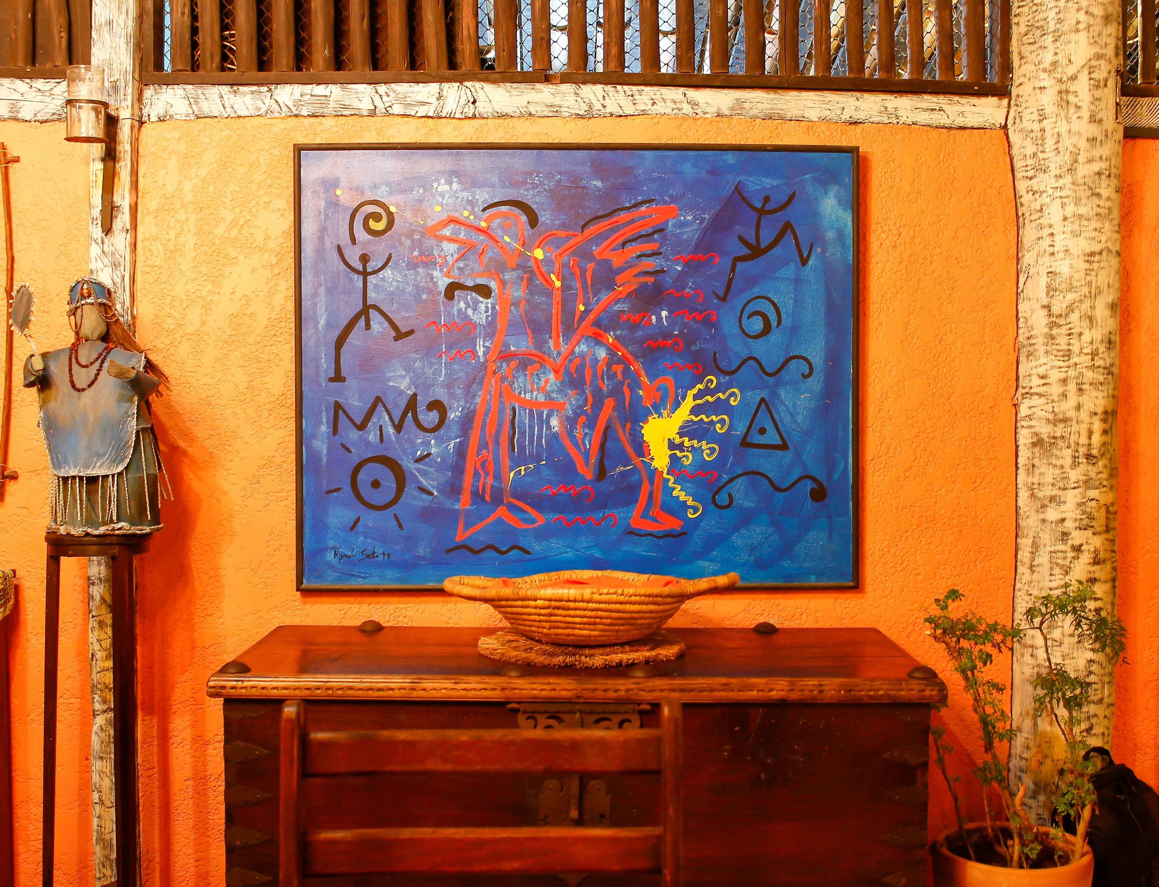 A room with a wooden cabinet, a wall-mounted painting, and a statue.
