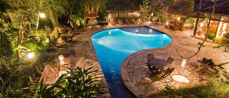 A landscaped outdoor area with a swimming pool, lounge chairs, and a gazebo.