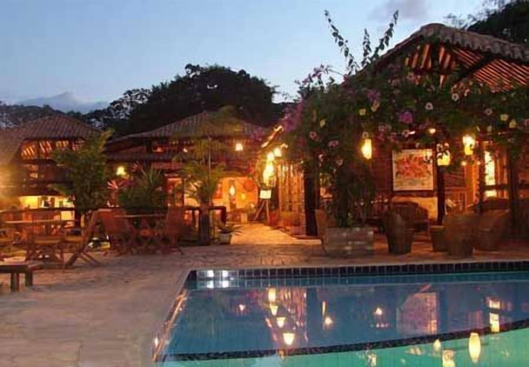 A poolside area with a clear view of the pool, lounge chairs, and a building with a thatched roof.