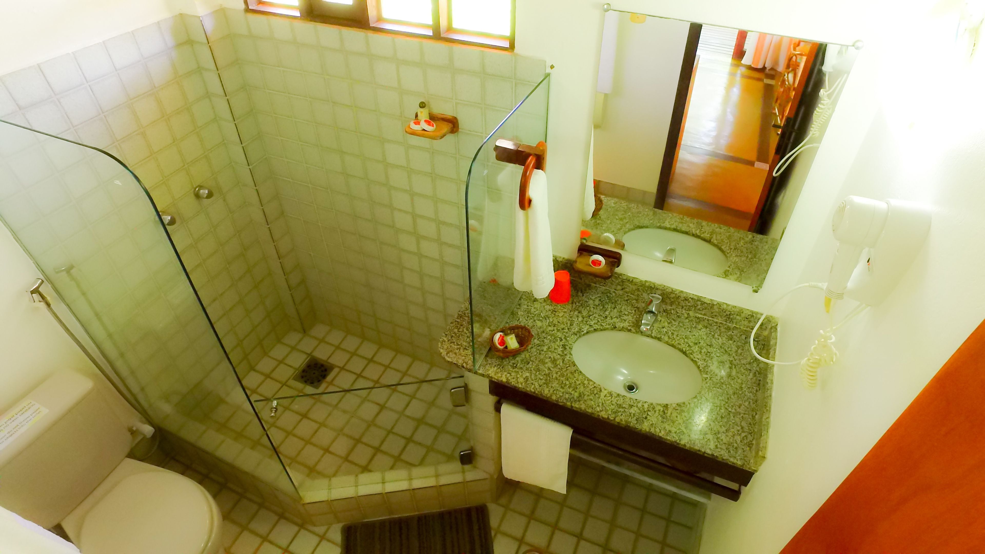 Un baño con cabina de ducha de vidrio, dos lavamanos y un inodoro.