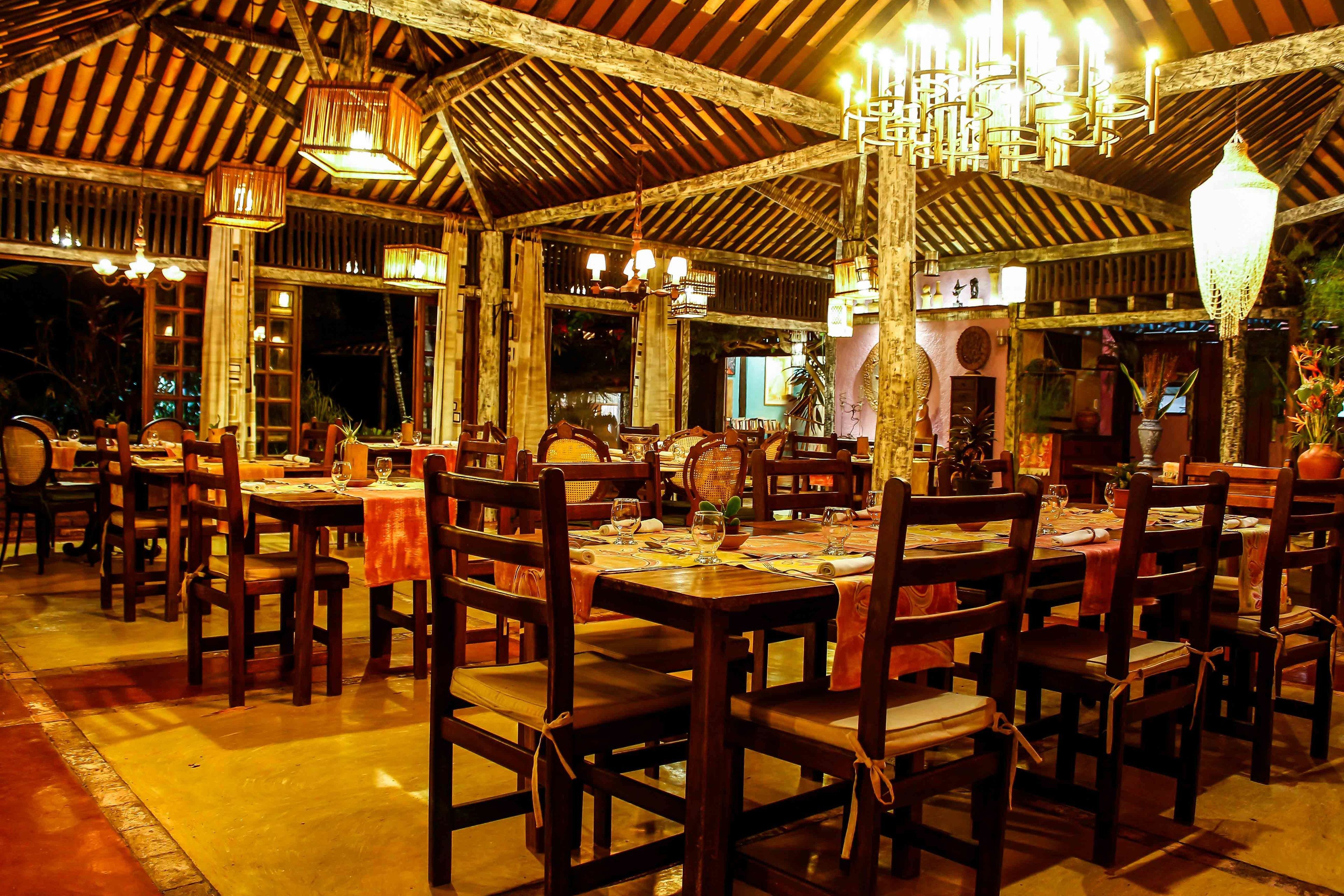 Ein Restaurant mit Holztischen und -stühlen, hängenden Laternen und einem Kachelboden.