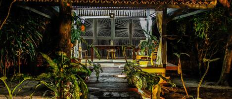A traditional-style building with a tiled roof, a central open area with a bench, and potted plants around.
