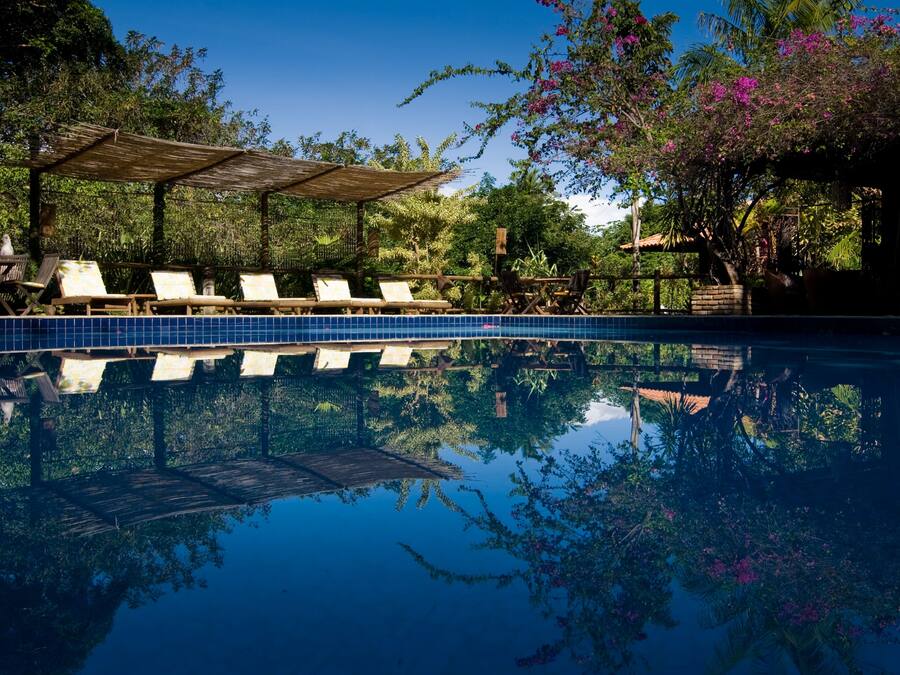 A pool area with lounge chairs and a wooden pergola.