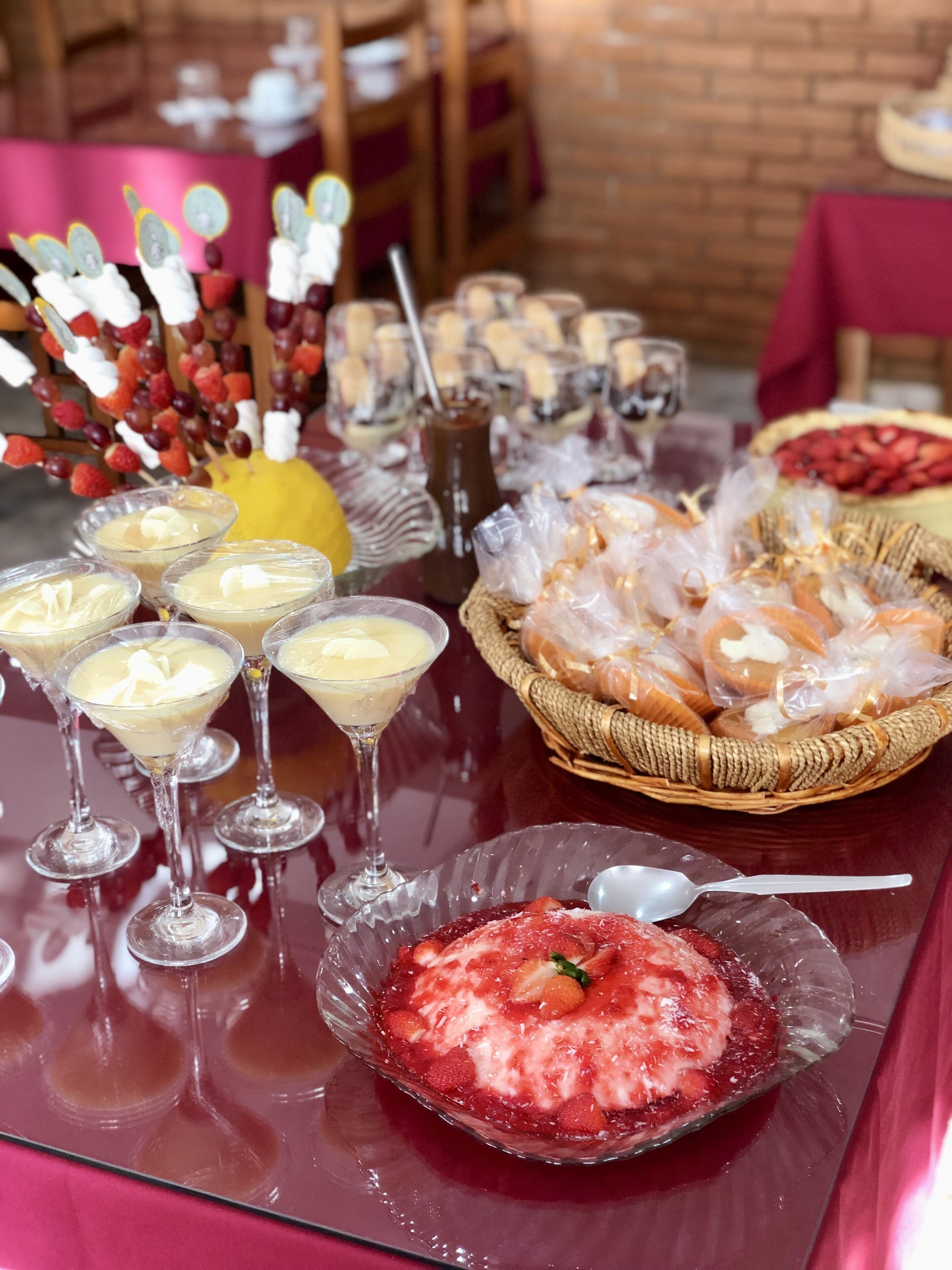 Ein Tisch mit verschiedenen Desserts und Getränken, darunter eine Schüssel Erdbeeren und ein Korb mit Brot.